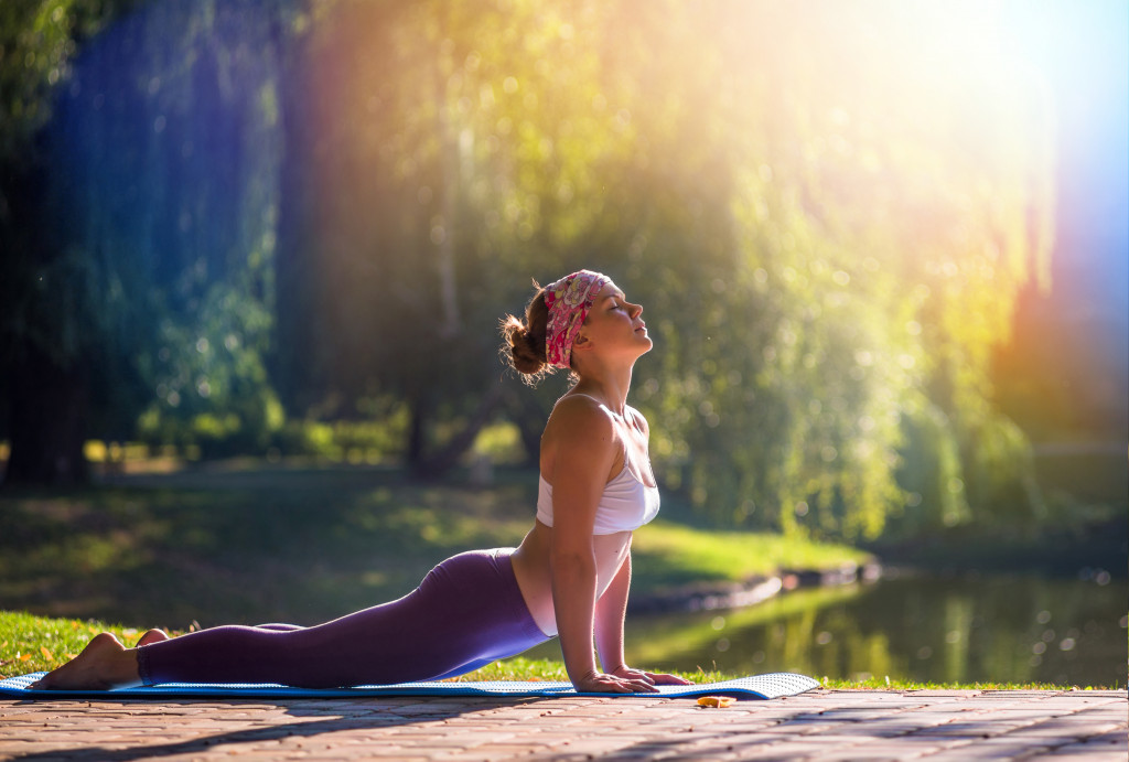 a young woman meditating and doing a yoga pose at the park