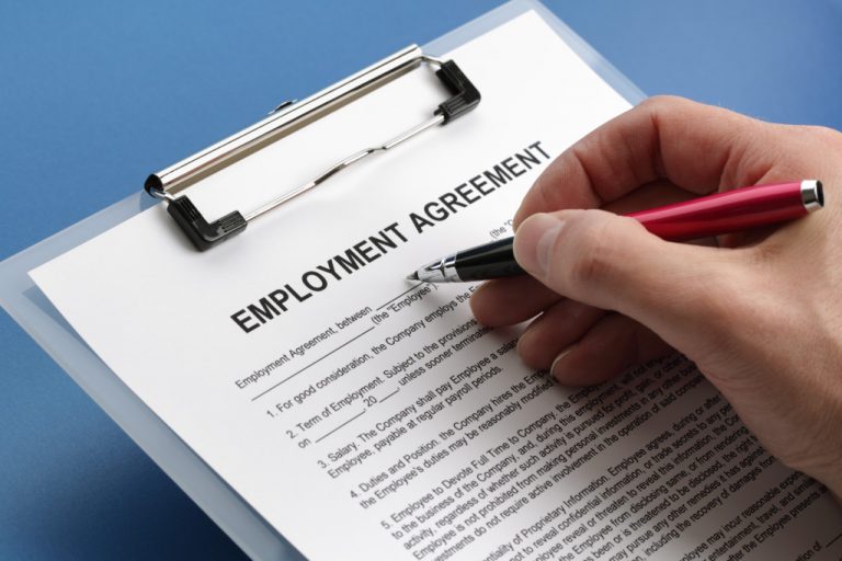 A hand filling out an employment agreement document