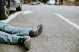 person lying on the ground after a car accident